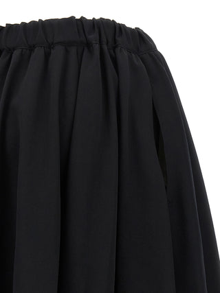 Black wool mini skirt by Comme Des Garçons, featuring a fitted design and stylish waistband, shown on a model.
