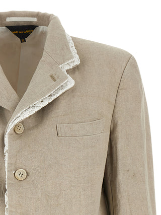 Beige linen blazer by Comme Des Garçons, tailored fit with classic lapel, shown on a hanger against a neutral background.