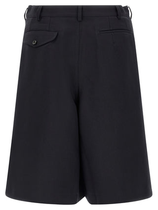 Blue polyester Bermuda shorts by Comme Des Garçons, shown on a model, featuring a relaxed fit and casual style.