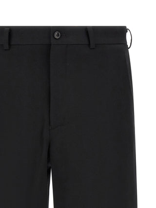 Black wool Bermuda shorts by Comme Des Garçons, featuring a tailored fit and classic design, shown on a model.