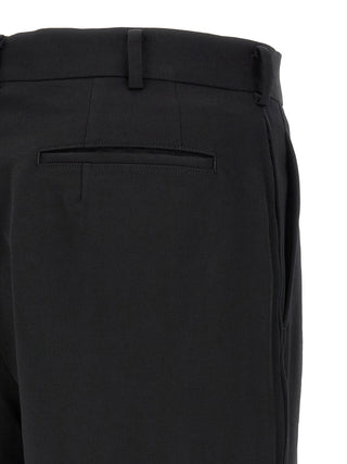 Black wool Bermuda shorts by Comme Des Garçons, featuring a tailored fit and classic design, shown on a model.