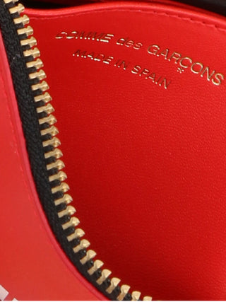 Red cowhide cardholder by Comme Des Garçons featuring multiple card slots and sleek minimalist design.