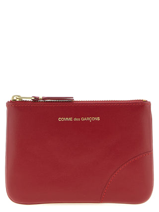 Red calfskin cardholder by Comme Des Garçons with multiple card slots and sleek minimalist design.