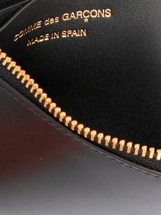 Black calfskin wallet by Comme Des Garçons featuring a sleek, minimalist design with multiple card slots and a secure bill compartment.
