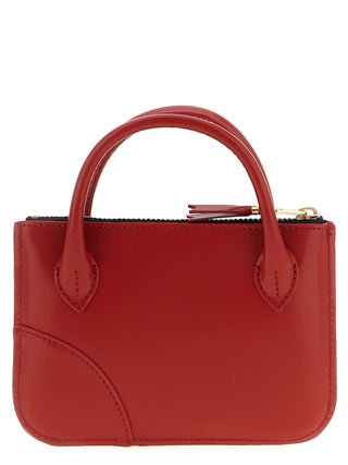 Red cowhide cardholder by Comme Des Garçons with multiple card slots and minimalist design.