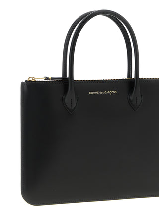 Black cowhide handbag by Comme Des Garçons featuring a sleek design with top handles and minimalist style.