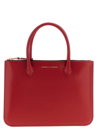 Red cowhide handbag from Comme Des Garçons with sleek design and sturdy leather strap, stylish accessory for everyday use.