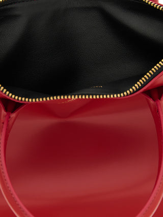 Red cowhide handbag by Comme Des Garçons featuring a sleek design and structured shape.