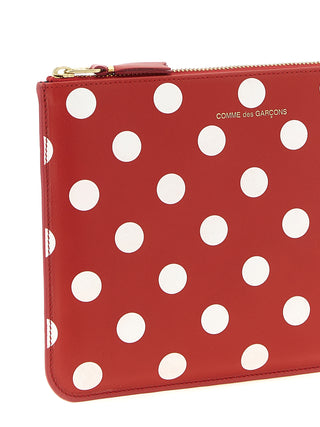 Red calfskin wallet by Comme Des Garçons featuring a sleek, minimalist design with a fold-over flap and subtle branding.