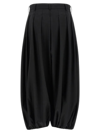 Black wool pants by Comme Des Garçons, stylish tailored trousers with a modern fit, shown on a model.