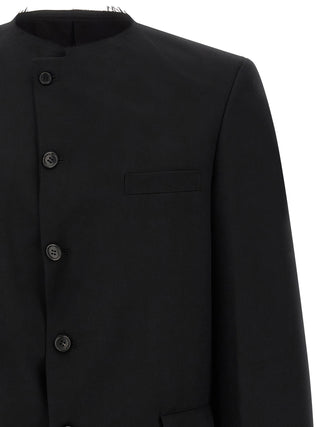Black wool blazer by Comme Des Garçons, tailored fit with notched lapels and button closure, displayed on a hanger.