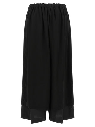 Black wool casual pants by Comme Des Garçons, featuring a relaxed fit and modern design, shown on a model.