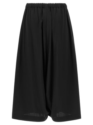 Black wool cropped pants by Comme Des Garçons, featuring a tailored fit and minimalist style, shown on a model.