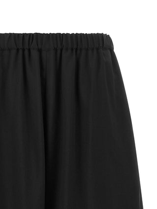 Black wool cropped pants by Comme Des Garçons, featuring a tailored fit and modern design, shown on a model.