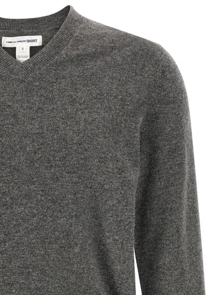 Gray wool cardigan by Comme Des Garçons, featuring a cozy knit texture and classic design, displayed on a hanger.