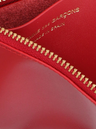 Red calfskin cardholder from Comme Des Garçons with multiple card slots and sleek minimalist design.