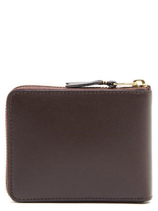 Brown cowhide leather wallet by Comme Des Garçons with stitched detailing and compact design.