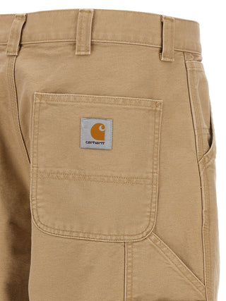 Beige organic cotton casual pants by Carhartt Wip, showing relaxed fit with side pockets and elastic waistband.
