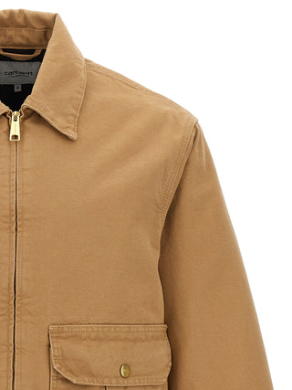 Beige Carhartt Wip full-length cotton jacket displayed on a hanger with front zipper and pockets.