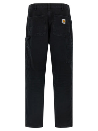 Black organic cotton straight-leg jeans by Carhartt Wip displayed on a hanger with front view and visible stitching details.