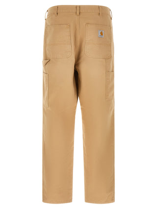 Brown organic cotton casual pants by Carhartt Wip, featuring a relaxed fit and classic design, shown on a model.