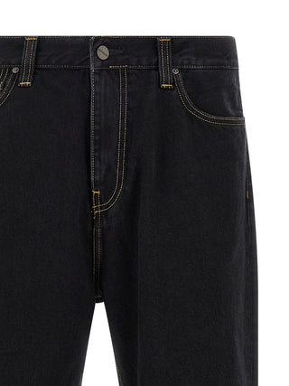 Black Carhartt Wip cotton tapered jeans with classic five-pocket design and fitted cut, shown on a hanger.