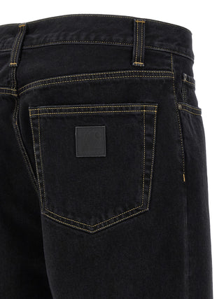 Black cotton tapered jeans by Carhartt Wip with a slim fit, displayed on a hanger against a neutral background.