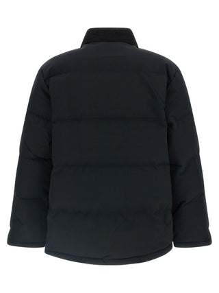 Black nylon shell jacket by Carhartt Wip with a hood, front zipper, and adjustable cuffs, designed for outdoor weather protection.