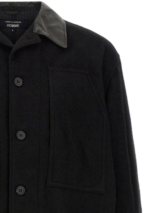 Black wool full-length jacket by Comme Des Garçons, displayed on a hanger, showcasing its sleek, minimalist design.