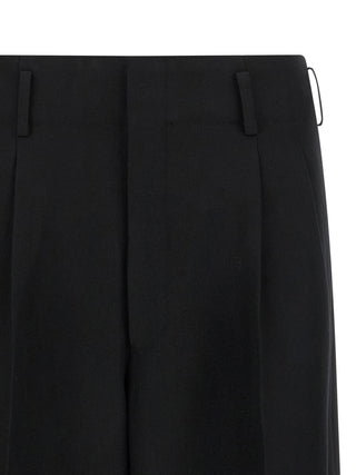 Black wool cropped pants by Comme Des Garçons, showcasing a tailored fit and minimalist design on a neutral background.