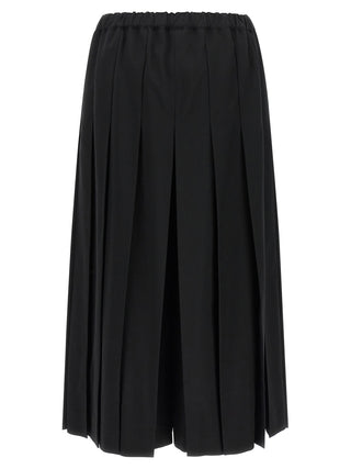 Black wool casual pants by Comme Des Garçons, featuring a relaxed fit and minimalist design, shown on a hanger.