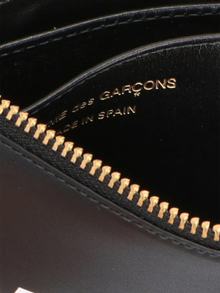 Black cowhide cardholder by Comme Des Garçons with multiple card slots and sleek minimalist design.