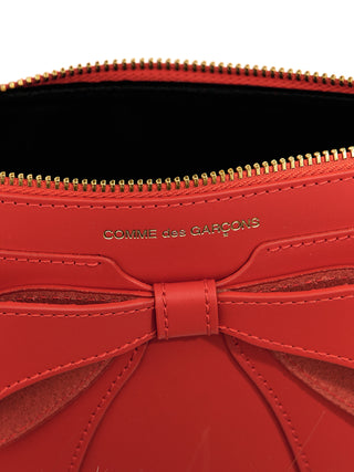 Red cowhide cardholder by Comme Des Garçons, featuring multiple card slots and sleek minimalist design.
